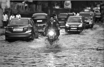  ?? SHAILESH ANDRADE / REUTERS ?? People commute along a water-logged street after rains in Mumbai, India, on Wednesday. The monsoon caused disruption to air and road transport and forced the closures of schools and colleges.