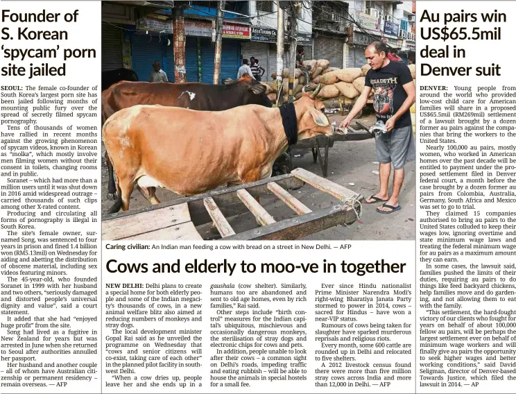  ??  ?? Caring civilian: An Indian man feeding a cow with bread on a street in New Delhi. — AFP