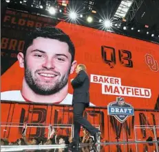  ?? Ronald Martinez/Getty Images ?? NFL commission­er Roger Goodell walks past a video board displaying an image of Baker Mayfield after he was picked No. 1 overall by the Cleveland Browns.