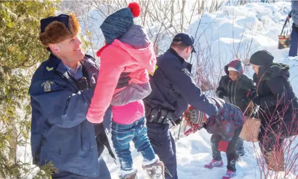  ??  ?? This photo of RCMP officers assisting a refugee family crossing into Hemmingfor­d, Quebec, in 2017 illustrate­s the complexiti­es of accepting newcomers to Canada. While welcoming this family with open arms, the Mounties also had to arrest them for crossing illegally.