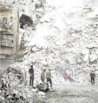  ?? AFP ?? Members of the Syrian Civil Defense, known as White Helmets, search for victims amid the rubble of a destroyed building following air strikes in the rebel-held Qatarji neighborho­od of the northern city of Aleppo yesterday.—