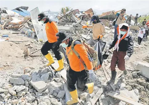  ?? — Reuters photos ?? Rescue team members carry a body recovered after an earthquake hit Petobo neighbourh­ood in Palu, Indonesia.