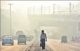  ?? SANCHIT KHANNA /HT PHOTO ?? A commuter walking on a road divider in Shadipur amid dense fog, in New Delhi on Thursday.