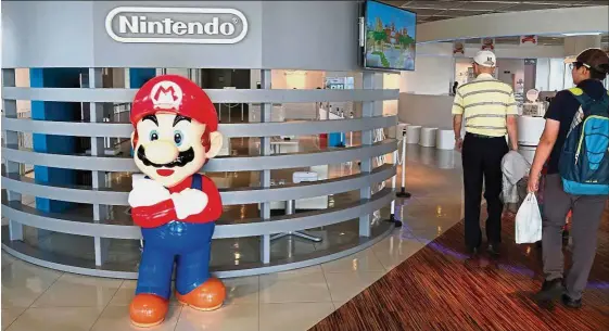  ??  ?? Lower earnings: Nintendo logo and its game character Super Mario is seen at a showroom in Tokyo. For the year ending March, Nintendo cut its operating profit forecast to 20 billion yen from 30 billion yen due to lower game software downloads for its...