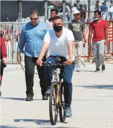  ??  ?? People walk and a man rides a bicycle along the seaside Corniche, as Lebanese authoritie­s warned of a new wave of the coronaviru­s disease (COVID-19), in Beirut.