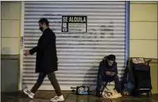  ?? ALVARO BARRIENTOS — THE ASSOCIATED PRESS ?? A homeless with his pet, in front a store, begs for alms in Pamplona, northern Spain, on Thursday. The Oxfam antipovert­y organiatio­n warns that “rigged economies” are aiding the rich, while the poor fall father behind during the coronaviru­s pandemic.