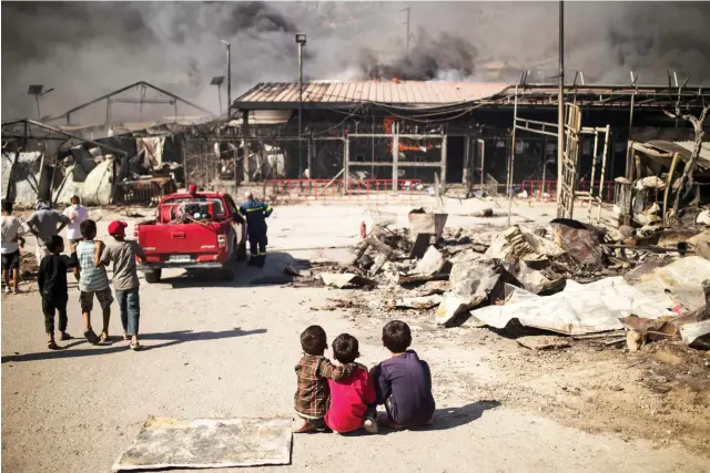  ?? AFP ?? Refugee children in a burnt-out camp on the Greek island of Lesbos after fire destroyed the site. Below: Aid agencies face growing difficulti­es keeping families together as increasing numbers flee conflict and economic hardship.