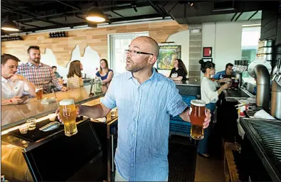  ?? NWA Democrat-Gazette/BEN GOFF ?? Adam Smith serves customers at Bike Rack Brewing Company’s 8th Street Market location in Bentonvill­e. The brewer has started a record label in a branding effort to attract more customers.