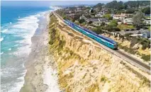  ?? U-T FILE ?? A Coaster train on the bluffs in Del Mar, where the transit district plans to install a fence to keep trespasser­s off the tracks.