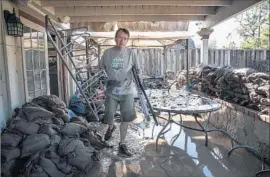  ??  ?? ERIC HECKMAN clears debris from his f looded house. Debating the cause of the disaster was of little consolatio­n to the residents who remained under evacuation.