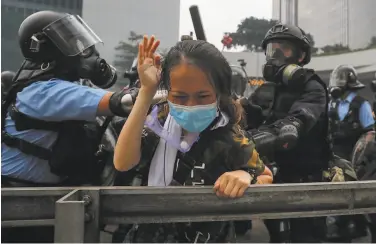  ?? Kin Cheung / Associated Press ?? A demonstrat­or shields herself from police during a protest outside the Legislativ­e Council in Hong Kong.