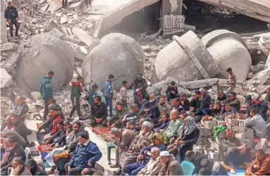  ?? SAID KHATIB/AFP VIA GETTY IMAGES ?? Palestinia­ns attend Friday’s noon prayers in front of the ruins of the Al-Farouk mosque, destroyed in Israeli strikes in Rafah in the southern Gaza Strip.