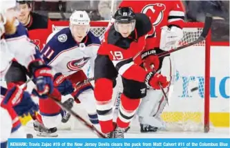  ?? — AFP ?? NEWARK: Travis Zajac #19 of the New Jersey Devils clears the puck from Matt Calvert #11 of the Columbus Blue Jackets during the second period on Tuesday at Prudential Center in Newark, New Jersey.