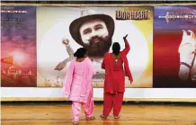  ??  ?? Devotees of Indian spiritual guru stands near a poster of his new film ‘MSG, The Warrior Lion Heart,’ in New Delhi, India.