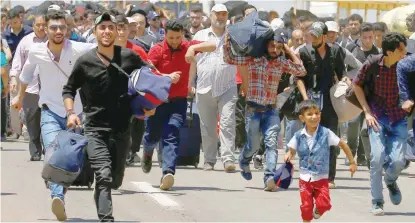  ?? — Reuters ?? A Syrian boy runs with the others, who say they are returning to Syria ahead of the Eid al Fitr, near the Turkish Cilvegozu border gate, located opposite of Syrian crossing point Bab al Hawa in Reyhanli, in the southern Hatay province, Turkey.