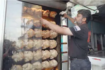  ?? — AFP ?? A shop owner sells broiled chicken in the town of Binnish, in Syria’s rebel-held northern Idlib province, on Monday.