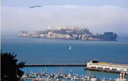  ??  ?? Picturesqu­e: a sailboat making its way past alcatraz Island, stage for clint eastwood and many others in San Francisco. (Pic below) People posing for pictures and a car making its way down Lombard Street with coit tower on telegraph Hill in the...