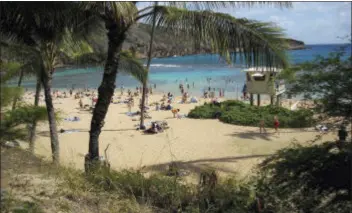  ?? AP FILE PHOTO ?? This Jan. 9, 2012 photo shows sunbathers and snorkelers enjoying a balmy beach day at Hanauma Bay, on the east side of Oahu, Hawaii. The bay is home to hordes of colorful tropical fish.