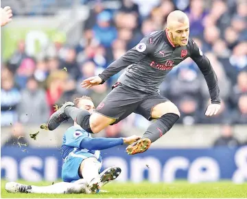  ?? — AFP photo ?? Brighton’s English striker Glenn Murray (L) is booked for this foul on Arsenal’s English midfielder Jack Wilshere during the English Premier League football match between Brighton and Hove Albion and Arsenal at the American Express Community Stadium in...