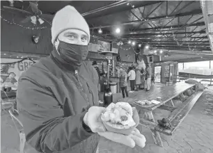  ?? PHOTOS BY MARK KURLYANDCH­IK/DETROIT FREE PRESS ?? Green Dot Stables chef-partner Les Molnar holds up a camel burger on the Corktown slider bar’s holiday patio on Tuesday.