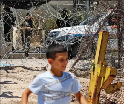  ?? JAAFAR ASHTIYEH / AFP ?? A boy plays in front of an Israeli barrier fence, near the site where a Palestinia­n was shot dead in the West Bank, on June 19.