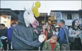  ?? WU HUANG / FOR CHINA DAILY ?? A young visitor checks out a performer wearing a unicorn mask during a carnival parade at the sixth Wuzhen Theatre Festival in Wuzhen, Zhejiang province, on Thursday. A record 29 theatrical works will be performed during the 11-day event.