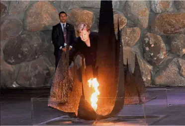  ?? AFP ?? Symbolic gesture: Merkel rekindling the eternal flame in the Hall of Remembranc­e in the Yad Vashem Holocaust Museum in Jerusalem. —