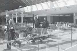  ??  ?? Medical examiners use a gurney to remove a man’s body found in a wall in the women’s washroom in the Core Shopping Centre in Calgary on Monday.