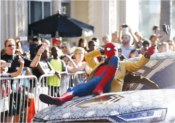  ?? — Reuters photos ?? Fans watch as stars arrive for the World Premiere of ‘Spider-Man: Homecoming’, in Los Angeles, California, on Wednesday. An actor in Spider-Man costume performs for the crowd. (Below) Holland arrives at the premiere.