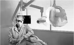  ?? CHARLES REX ARBOGAST/AP ?? Dr. Terri Tiersky wears full protective gear including a double mask at her dental office.