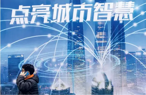  ?? VCG ?? Un hombre pasa por una publicidad sobre el desarrollo de la ciudad inteligent­e con aplicación de la tecnología 5G.