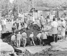  ??  ?? Workers inspect a road damaged by Typhoon Nock-Ten in Tabaco, Albay province. — AFP photo