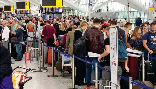  ??  ?? Grounded: Passengers are forced to wait in line to manually check in at BA departure desks at Heathrow yesterday