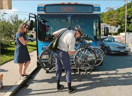  ?? DANA JENSEN/THE DAY ?? After placing her bicycle on the bike rack, Maggie Redfern, left, waits for Andrew Lopez, both of New London, to finish securing his bicycle before they board the bridge sidewalk shuttle bus at the Williams Street shuttle stop in New London to the Riverview Avenue shuttle stop in Groton on Thursday. Redfern and Lopez do not own cars and were planning to ride their bicycles to Mystic to see a movie. People wanting to use the pedestrian sidewalk on the Gold Star Memorial Bridge are having to use the shuttle while the sidewalk is closed for repairs.