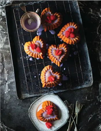  ?? PHOTOS: ALAN BENSON/POH BAKES 100 GREATS ?? Poh Ling Yeow’s heart-shaped mini cakes have a delicious orange flavour and are topped with a violet glaze and raspberrie­s — perfect for a tasty Valentine’s Day treat.