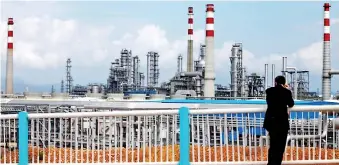  ??  ?? A visitor looks at China National Offshore Oil Corporatio­n’s (CNOOC) oil refinery in Huizhou, China’s southern Guangdong province