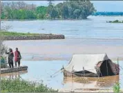  ?? AFP ?? People stand on the banks of a flooded area after heavy rains in Nowshera district, Khyber-Pakhtunkhw­a province.