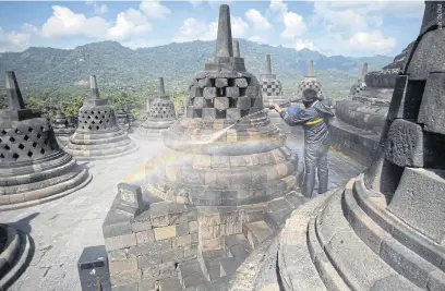  ??  ?? LEFT
A worker cleans volcanic ash off a stupa at the Borobudur Temple in Central Java on June 22, a day after an eruption by Mount Merapi. The temple is among the popular destinatio­ns that have started to reopen to domestic travellers in Indonesia.