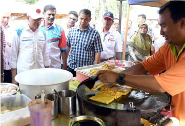  ??  ?? Anwar (left) stop by the murtabak stall while on his campaign trail at Pasar Tani Batu 4. — Bernama photo