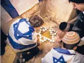  ?? ARIEL SCHALIT/AP ?? Youths light candles Sunday at the site of a shooting that left an Israeli immigrant dead in Jerusalem.