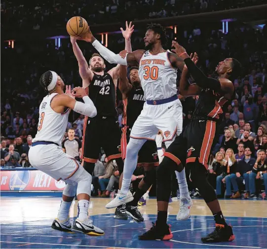  ?? ELSA/GETTY ?? The Knicks’ Julius Randle (30) reaches for a loose ball as the Heat’s Kevin Love (42) and Bam Adebayo (13) defend during Game 2 of their Eastern Conference semifinal series at Madison Square in New York.