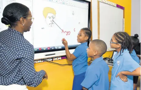  ?? IAN ALLEN/PHOTOGRAPH­ER ?? Jahssett Malcolm (left), senior accounts manager, Massy Technologi­es, shows students at the Port Royal Primary School how the interactiv­e SMART board is used. Port Royal Primary and Infant School received US$10,000 through a grant from the Silicon Valley Charity Foundation to purchase the high-tech SMART board to enhance its informatio­n technology programme and improve the teaching and learning at the school.