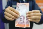  ?? — Reuters ?? A man shows the new five Bolivar Soberano (Sovereign Bolivar) bills, after he withdrew them from an automated teller machine (ATM) at a Mercantil bank branch in Caracas.