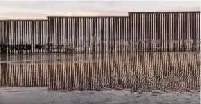  ??  ?? A girl runs towards the sea by the US border fence separating San Diego from Tijuana.