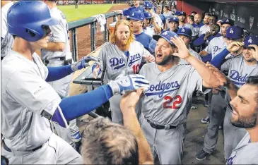  ?? LOS ANGELES TIMES ?? The Dodgers’ Cody Bellinger (left) is congratula­ted by teammates in the fifth inning Monday after his solo home run against Arizona. Game 3 of the NLDS at Chase Field ended with an L.A. win and a series sweep.