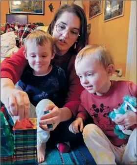  ?? (AP/Robert F. Bukaty) ?? Heather Cimellaro builds a toy house Wednesday with her twins, Milo (left) and Charlie, at their home in Auburn, Maine. Heather Cimellaro is one of many parents concerned about the omicron surge and the dilemma it’s posing for families of children too young to be vaccinated.