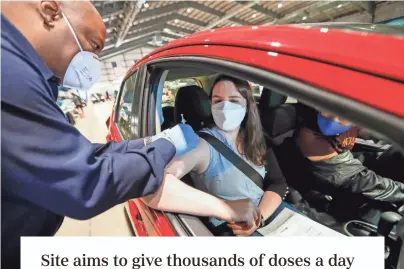  ??  ?? Columbus Division of Fire’s Mark Hill gives the Pfizer-biontech vaccine to Anne Christense­n, 34, and Sythan Pok, 34, of Clintonvil­le at the Columbus Public Health drive-thru vaccine clinic at the State Fairground­s on Monday.