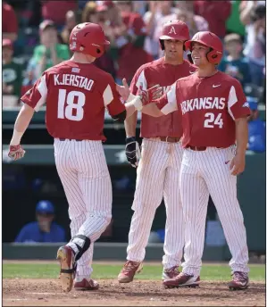  ?? NWA Democrat-Gazette/ANDY SHUPE ?? Arkansas left fielder Heston Kjerstad (18) is congratula­ted at the plate by Dominic Fletcher (24) and Jordan McFarland after hitting a three-run home run Saturday during the third inning of a first-game victory at Baum Stadium in Fayettevil­le.