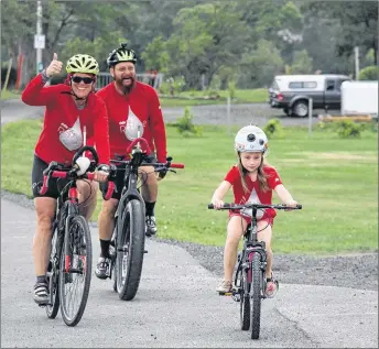  ?? SUEANN MUSICK/ THE NEWS ?? Andrea Haughan gives a thumbs-up to supporters as she cycles into Pictou with her husband Lloyd McLean and Reese Hawkins at the end of the Ride for Reese.