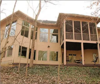  ??  ?? The main level has a screen-enclosed porch with carpeting and a paddle fan and is accessible from the breakfast room and the main bedroom. The porch opens out to a balcony deck with steps that lead down to the lower deck and wooded backyard.